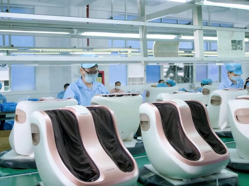Workers assembling massage products in rows along a factory production line.