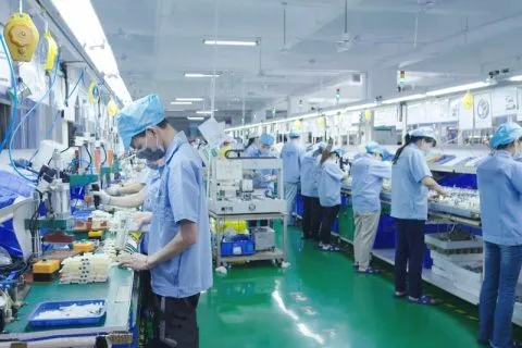 Factory operator checking products and components along a clean production line.